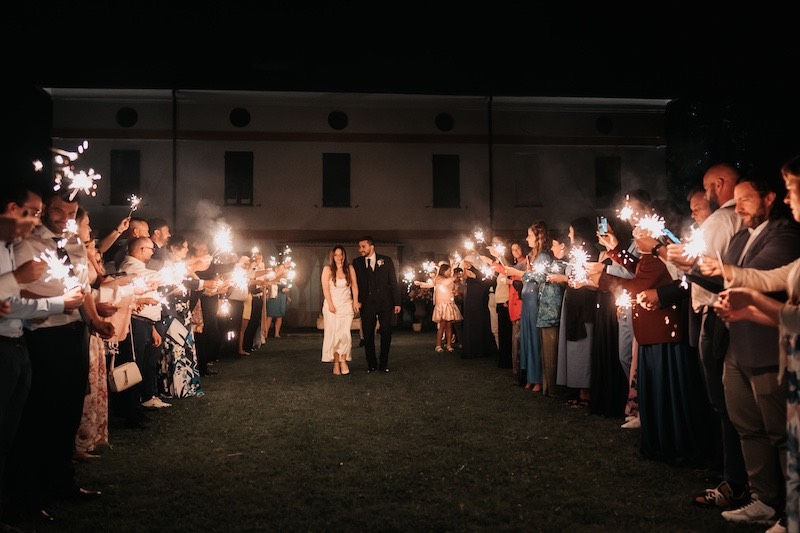 In questa foto di Federico Gritti due sposi mentre camminano tra la folla degli invitati che tengono in mano delle scintille luminose