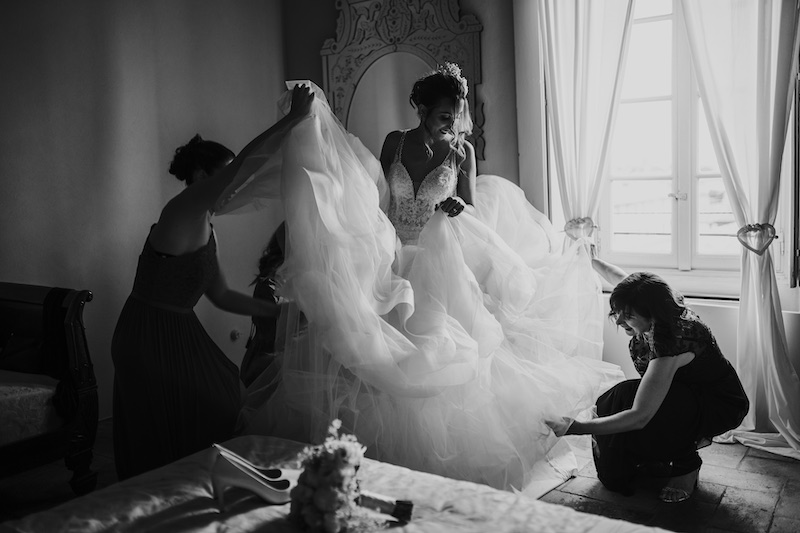 In questa foto in bianco e nero di Federico Gritti una sposa mentre indossa l'abito con le damigelle