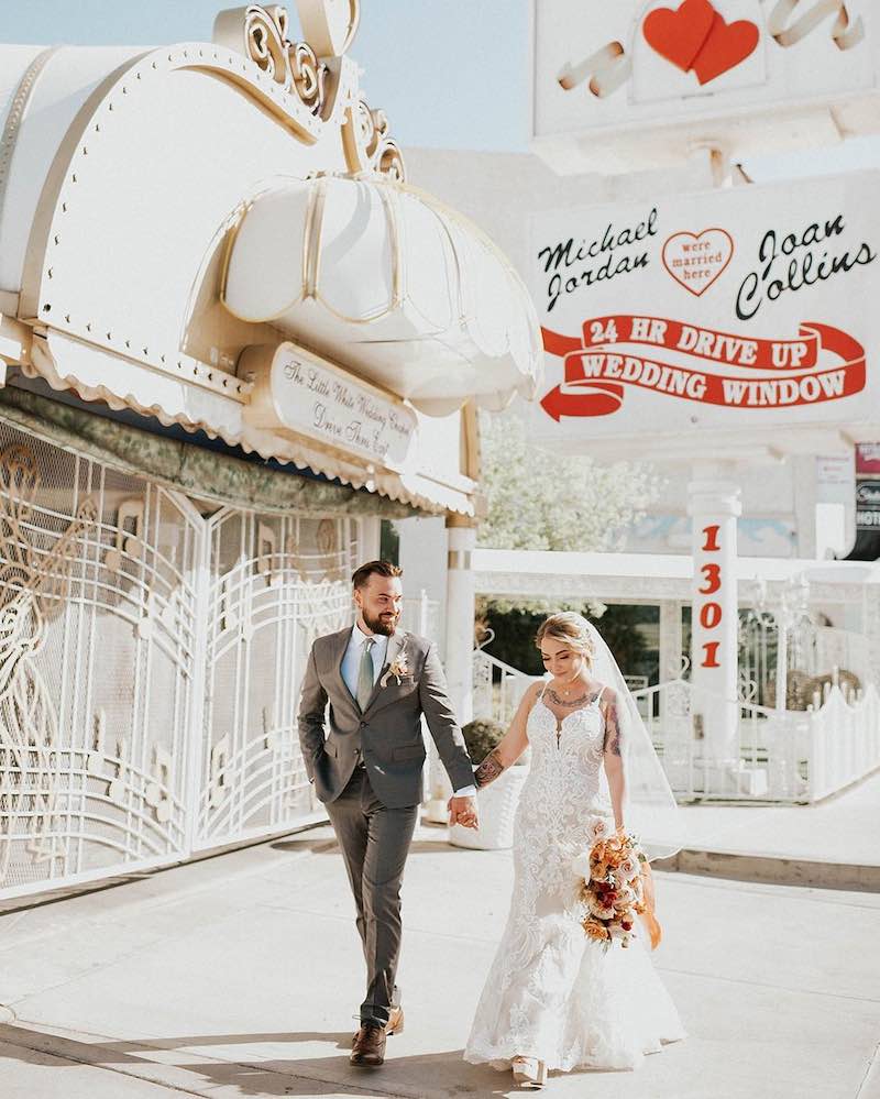 In questa foto, due sposi camminano  davanti ad una Love Chapel di Las Vegas tenendosi mano nella mano