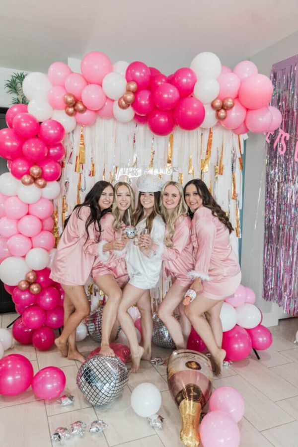 In questa foto, una sposa e quattro amiche festeggiano durante un Bachelorette Party tra palloncini di colore rosa, bianco e fucsia