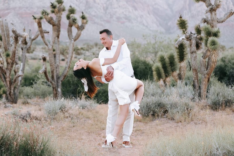 In questa foto, due sposi danzano felici nel deserto di Las Vegas, tra piante grasse. Lei indossa un abito corto e sandali con un fiocco posteriore