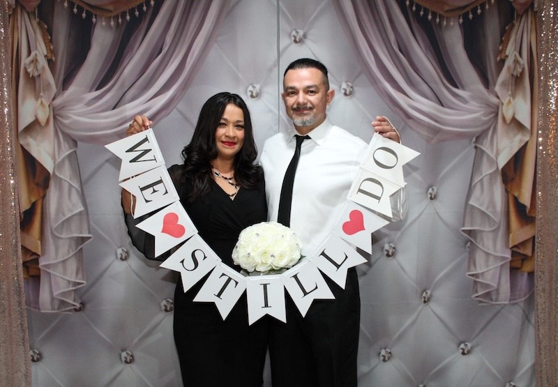In questa foto, due sposi posano con uno striscione con scritto "We Still Do" all'interno della Affinity Forever Wedding Chapel