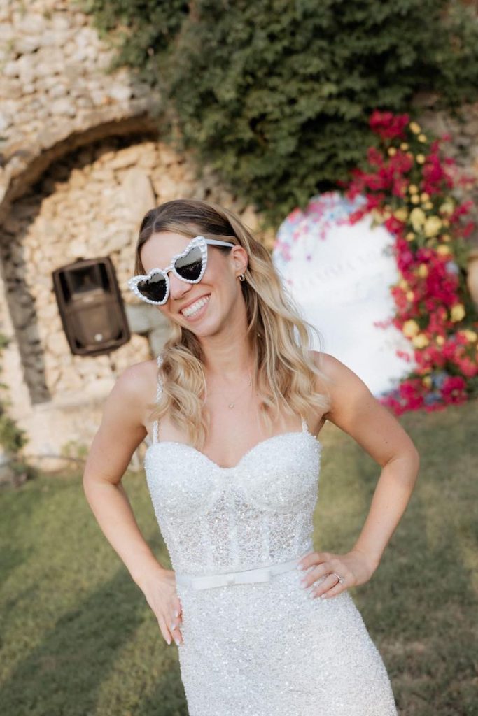 In questa foto, una sposa con occhiali a cuore di colore bianco
