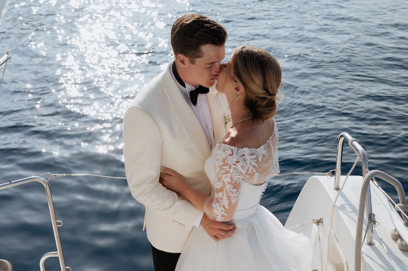 In questa foto, due sposi si baciano a bordo di un catamarano
