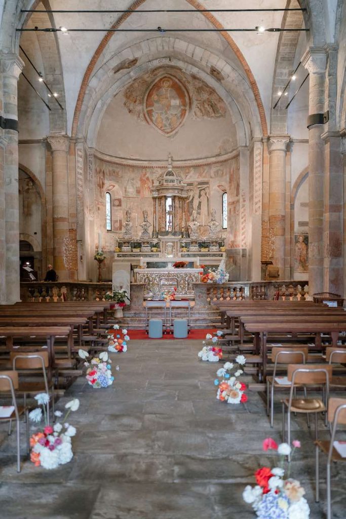 In questa foto, la navata centrale della chiesa matrimonio di Sarah e Loris firmato Lovevery Weddings&Events allestito con fiori colorati