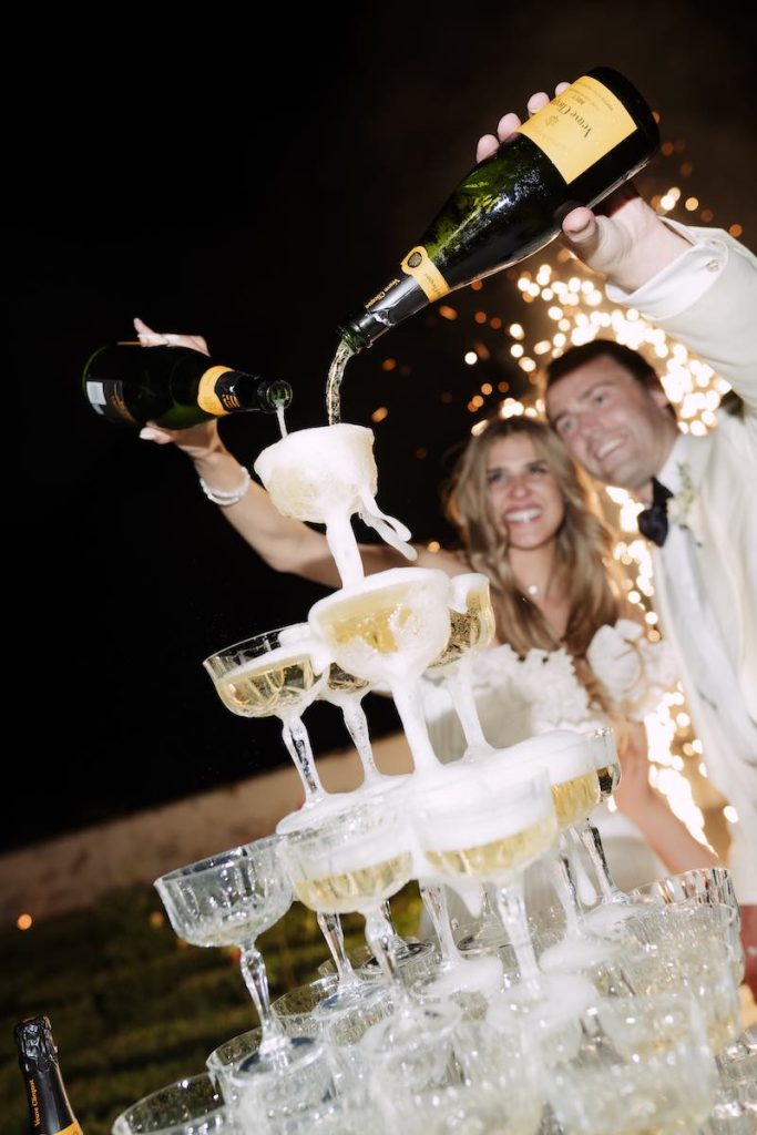 In questa foto, due sposi riempiono le coppe della loro Champagne Tower
