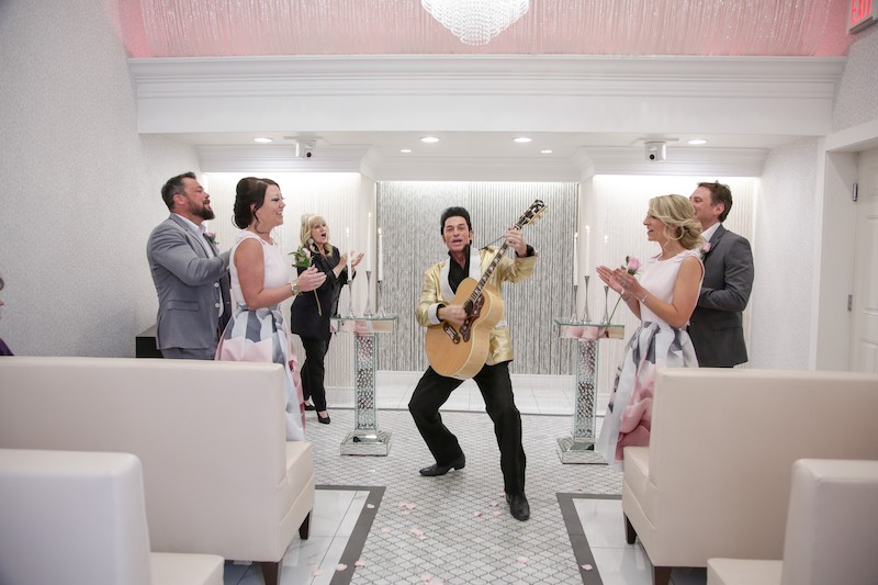 In questa foto, alcuni invitati ad un matrimonio battono le mani in una Love Chapel di Las Vegas con un figurante che interpreta Elvis Prestley