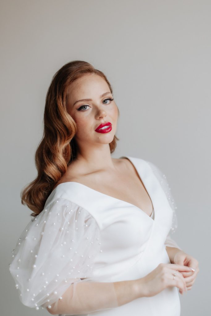 in questa foto si vede un'acconciatura sposa capelli lunghi sciolti sulle spalle con onde morbide dietro le spalle. la sposa ha i capelli rossi