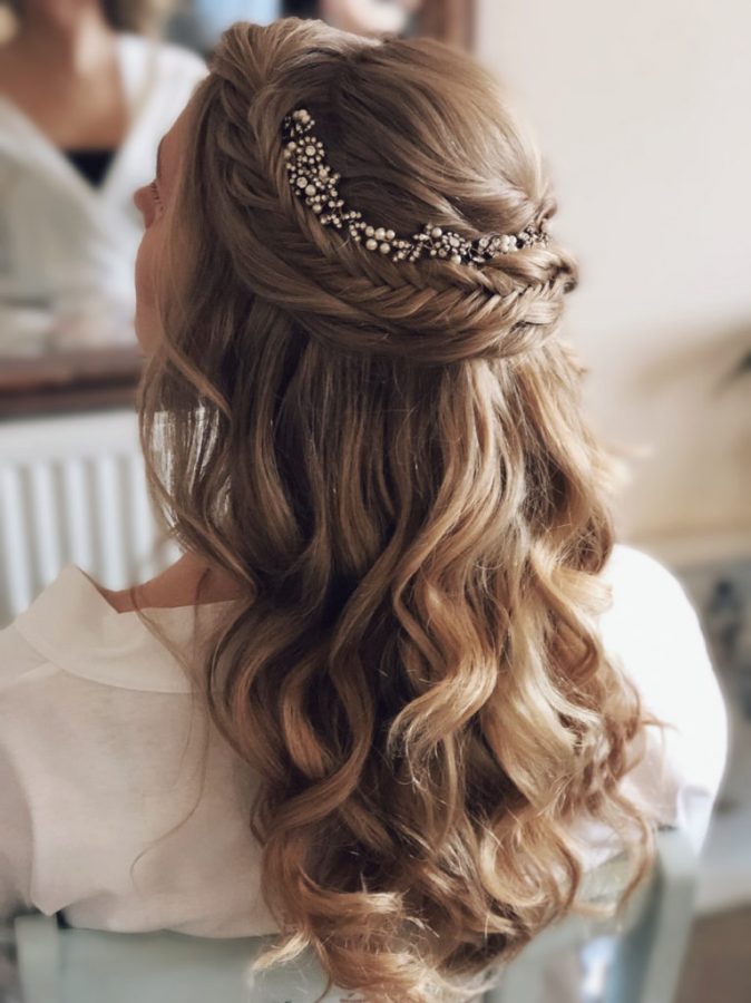 in questa foto si vede un'acconciatura sposa capelli medi acconciati con un mezzo raccolto con treccia, la sposa ha i capelli color castano chiaro e per per impreziosire l'acconciatura ha usato una tiara con decorazioni floreali che incornicia la treccia
