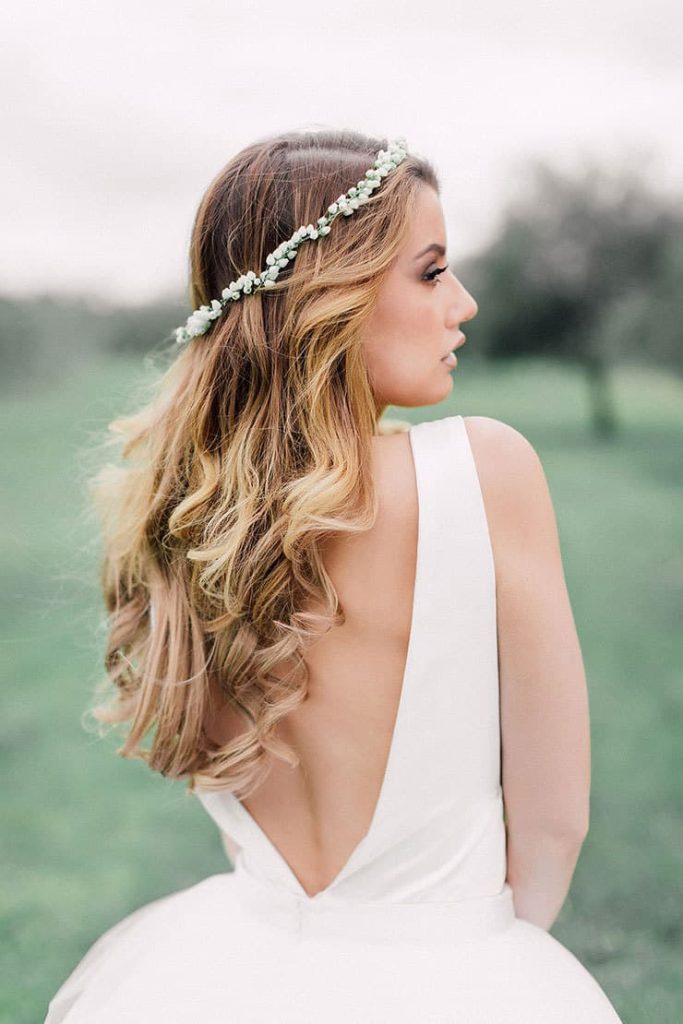 in questa foto si vede un'acconciatura sposa capelli medi, con corona floreale e beach waves. la sposa ha i capelli color biondo caldo e per per impreziosire l'acconciatura ha usato una piccola coroncina di fiorellini bianchi e tondi