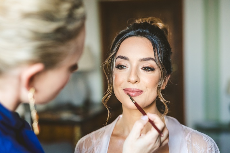 In questa foto, la make-up artist Annartstyle di spalle mentre trucca una sposa 