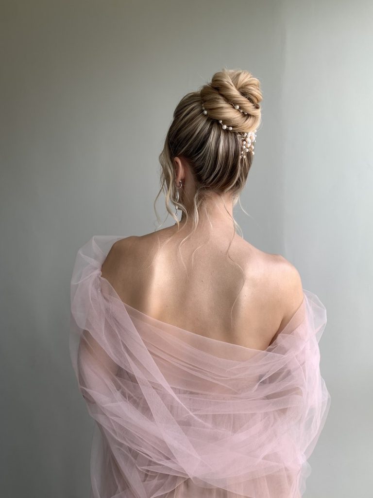 In questa foto, un'acconciatura da sposa con chignon alto decorato con perline