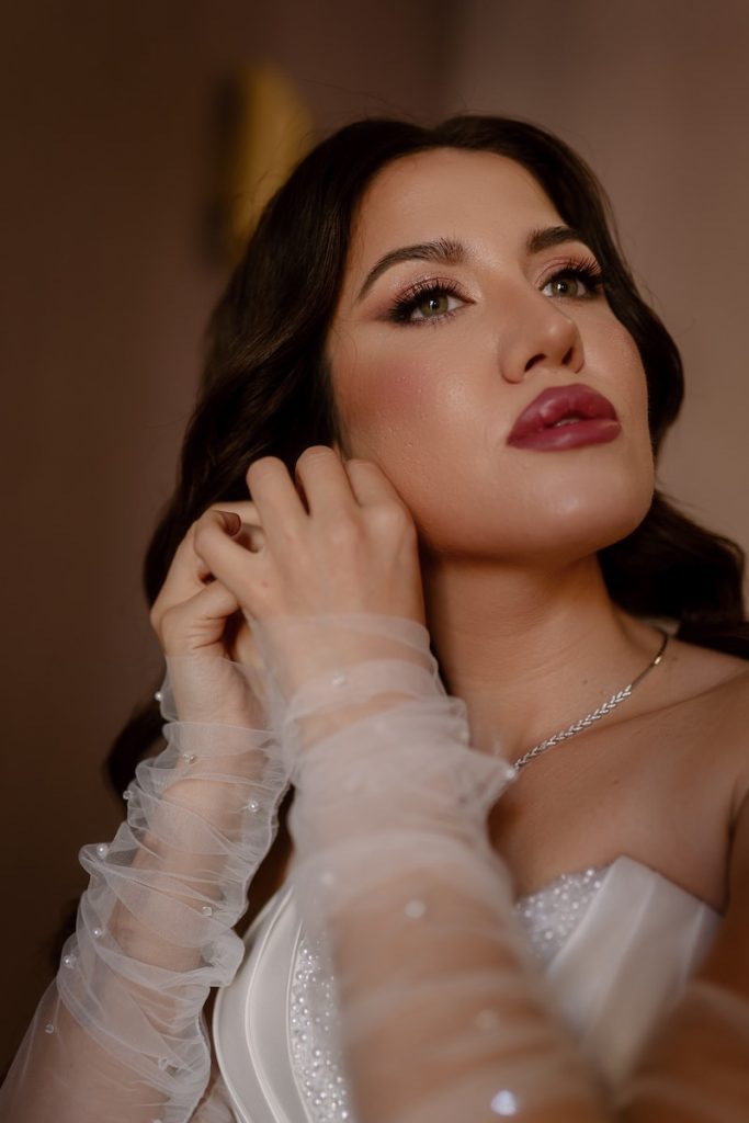 In questa foto, una sposa con un trucco deciso: sulle labbra indossa un rossetto color prugna e sugli occhi una linea di eyeliner 