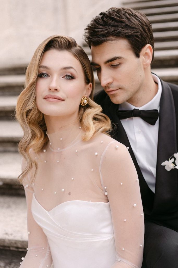 In questa foto, una sposa e uno sposo seduti su una scalinata. Lei mostra un trucco sposa naturale realizzato da Annartstyle