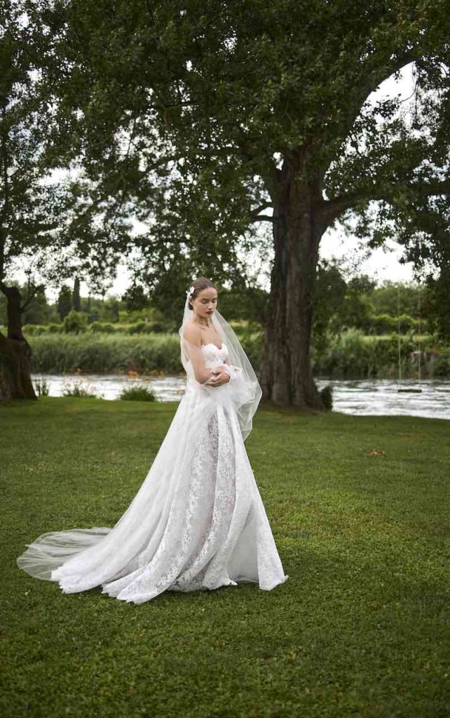 In questa foto, una modella posa con un abito da sposa scivolato in pizzo Chantilly della collezione sposa Elisabetta Polignano 2026