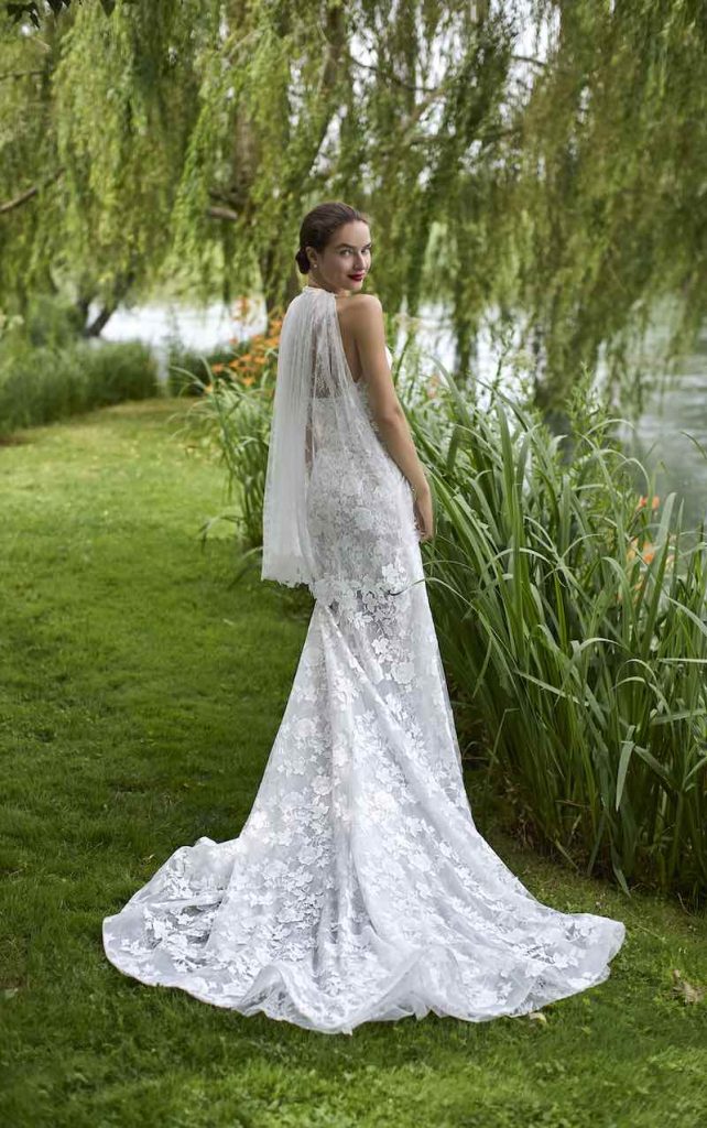 In questa foto, una modella di spalle posa con un abito da sposa a sirena in pizzo floreale