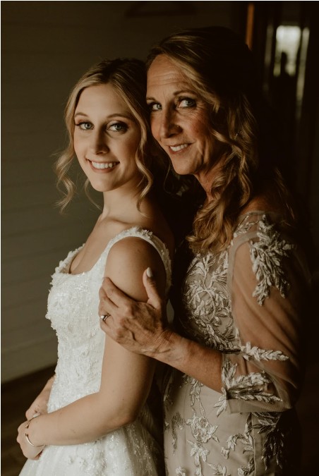 In questa foto, un primo piano mette in risalto una sposa dallo sguardo intenso, incorniciato da un trucco elegante e naturale: incarnato luminoso, labbra nude e occhi definiti da eyeliner e ciglia folte. Indossa guanti trasparenti in tulle e un paio di orecchini di perla. La sua posa con le mani incrociate sotto il viso trasmette grazia e raffinatezza. L'immagine rappresenta un perfetto esempio di come scegliere trucco sposa per esaltare la bellezza naturale mantenendo uno stile sofisticato.