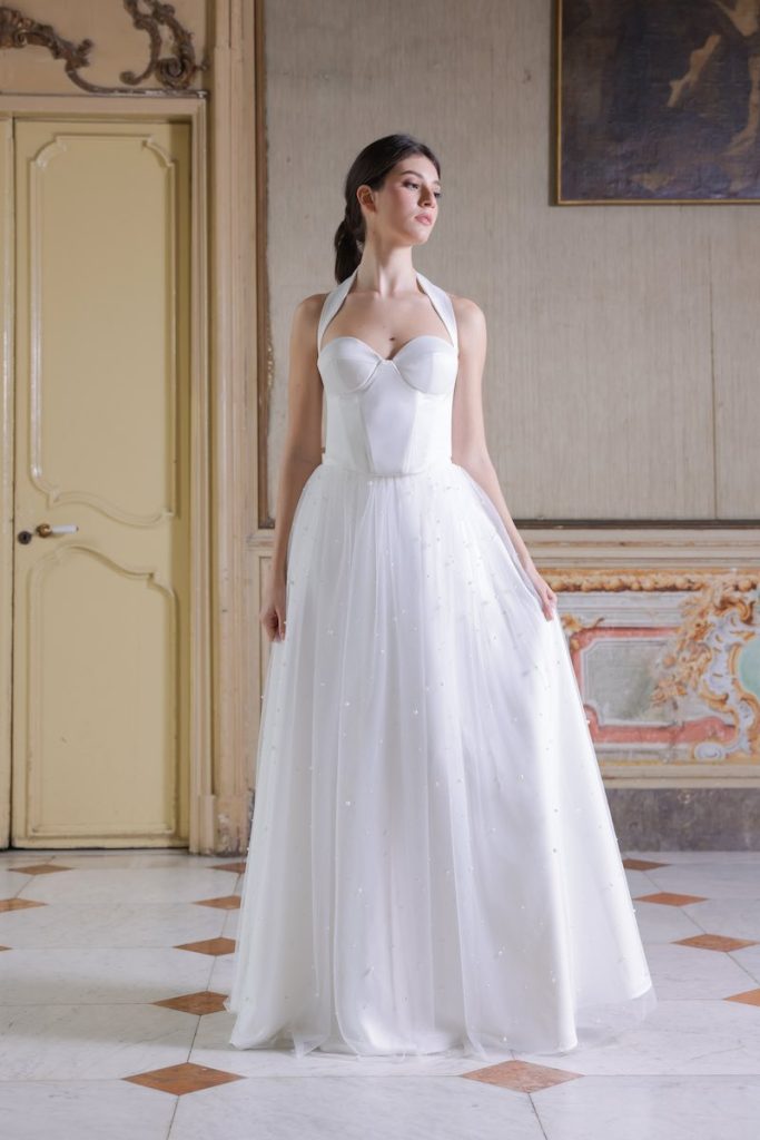 In questa foto, una modella indossa un abito da sposa Atelier Benedetta con gonna a ruota ricamato con perline e corpetto bustier con scollo a cuore