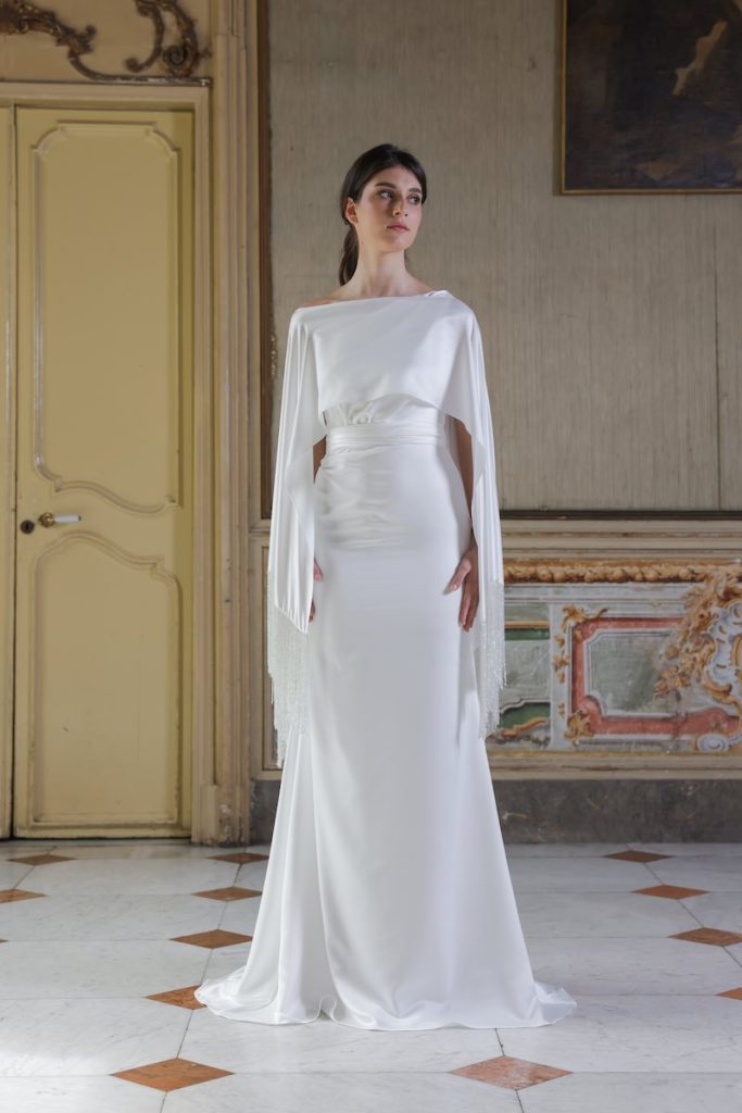 In questa foto, una modella indossa un abito da sposa 2026 modello a sirena con cappa in satin con frange