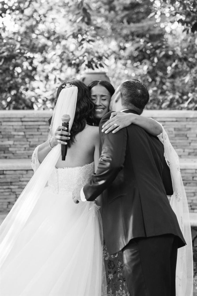 In questa foto in bianco e nero, la mamma della sposa abbraccia i due sposi alla fine della cerimonia