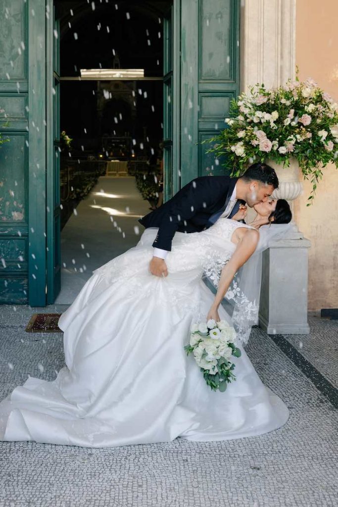 In questa foto, gli sposi Eleonora e Danilo si baciano con un casqué davanti all'ingresso della Basilica di Santa Cecilia in Trastevere