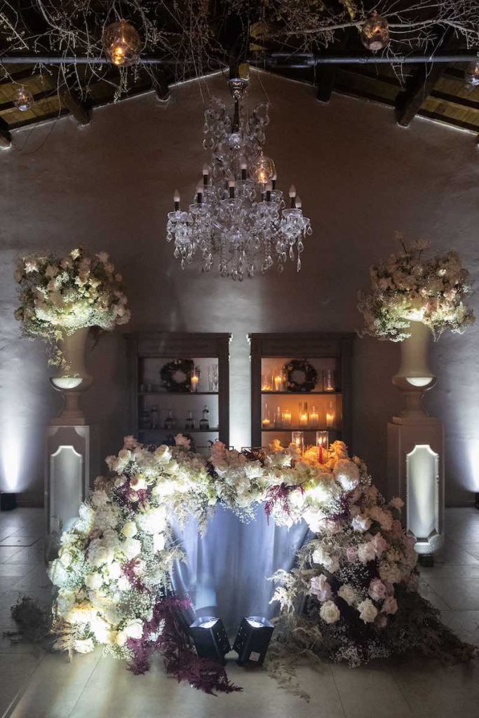 In questa foto, il dettaglio del tavolo degli sposi allestito dalla Wedding Planner Barbara Vissani con fiori di colore bianco e rosa, grandi composizioni e lampadari di cristallo