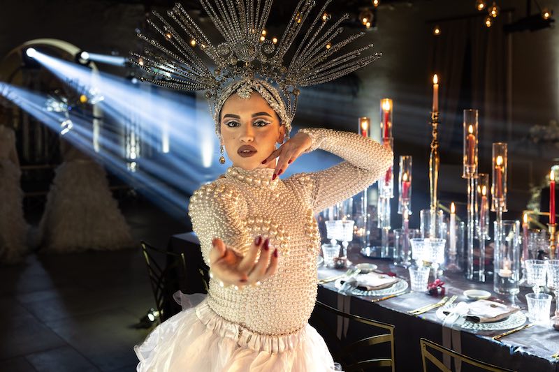 In questa foto, una performer del matrimonio di Barbara Vissani, che indossa un abito di colore bianco decorato con perle di varie dimensioni e una grande corona di cristalli