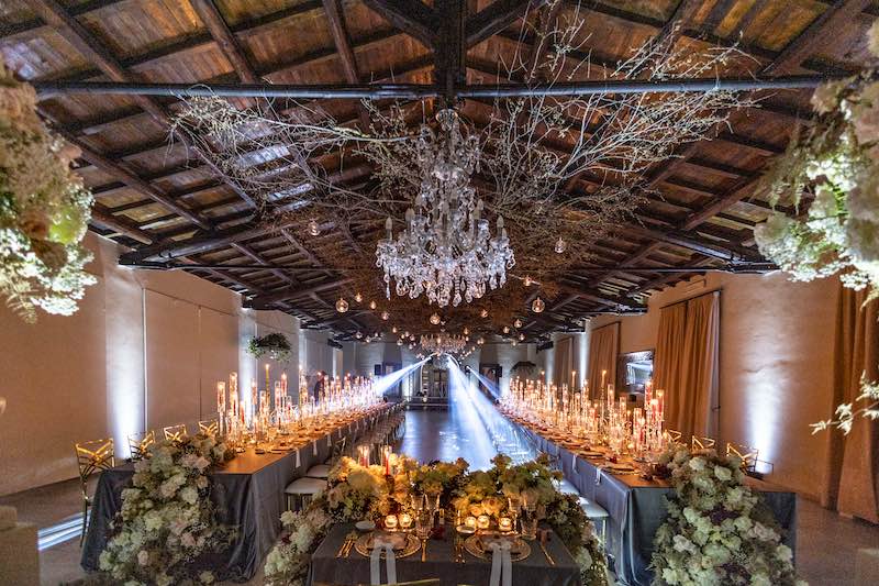 In questa foto, l'allestimento del ricevimento di Barbara Vissani con lampadari in cristallo, due tavoli imperiali decorati con fiori bianchi e candele di diverse altezze 