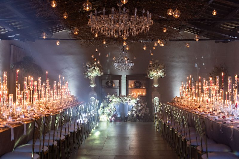 In questa foto, l'allestimento del ricevimento di Barbara Vissani con lampadari in cristallo, due tavoli imperiali decorati con fiori bianchi e candele di diverse altezze 