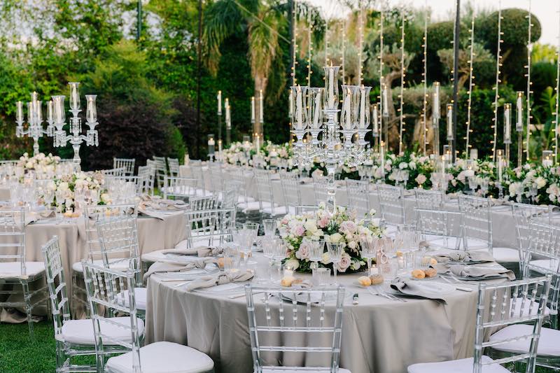 In questa foto, l'allestimento dei tavoli di un matrimonio progettato da Giorgia Pirro nei toni del grigio perla, con fiori di colore rosa e bianco, con candelabri di cristallo e candele