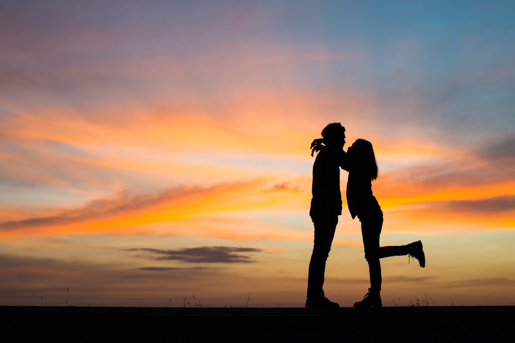 Coppia innamorata al tramonto che si abbraccia, si vedono solo le silhouette 
