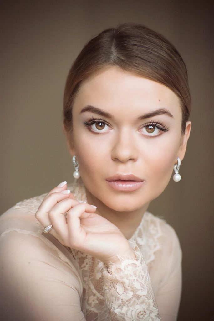 In questa foto, un primo piano di una sposa con un trucco naturale e un'acconciatura con uno chignon