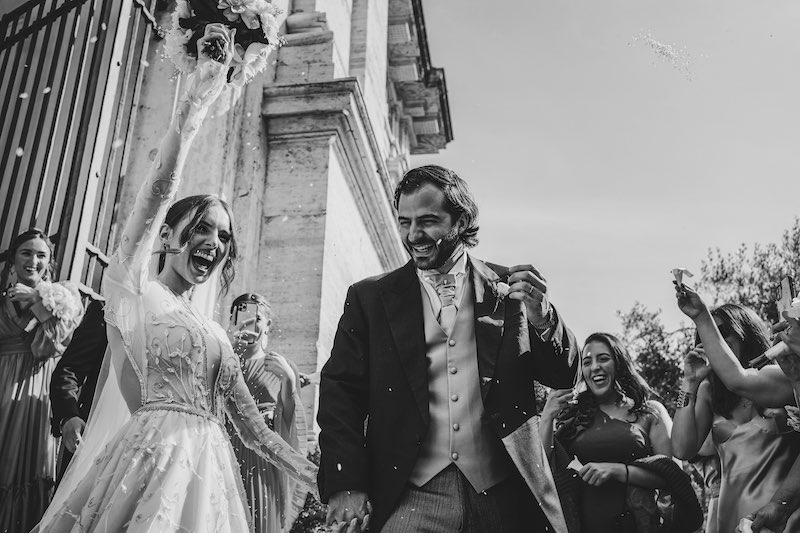 In questa foto in bianco e nero, due sposi felici ripresi leggermente dal basso all'uscita dalla chiesa
