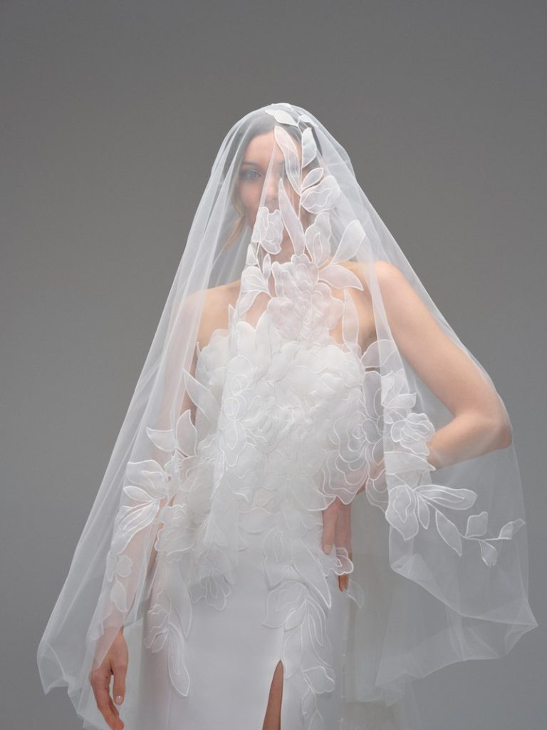 In questa foto, una modella indossa un velo da sposa in tulle di seta con applicazioni floreali 