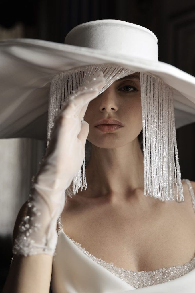 In questa foto, una modella posa indossando un capello da sposa a tesa larga con perline chandellier