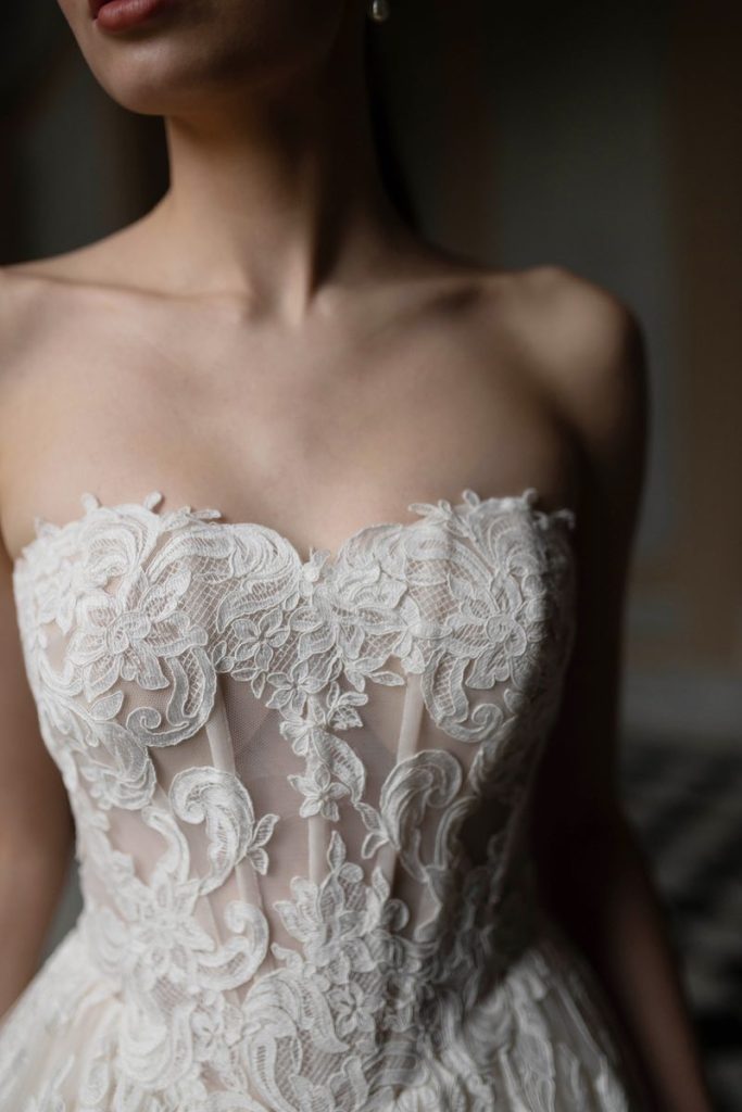 In questa foto, il dettaglio del corpetto bustier con ricami in pizzo Chantilly di un abito da sposa 2026 