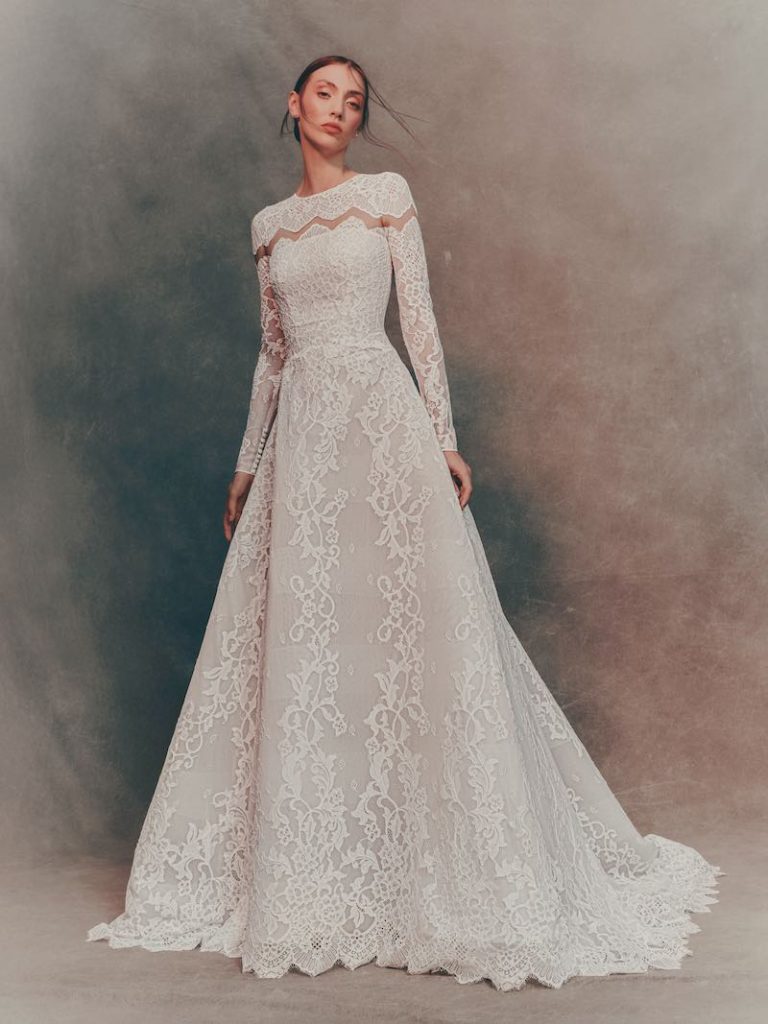 In questa foto, una modella indossa un abito da sposa trasformabile Atelier Pronovias 2026 ad A con maniche lunghe in pizzo 