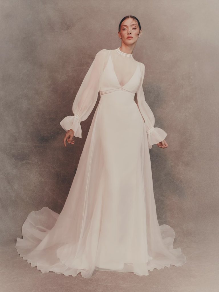 In questa foto, una modella indossa uno degli abiti da sposa Atelier Pronovias in organza, modello scivolato, a maniche lunghe e girocollo