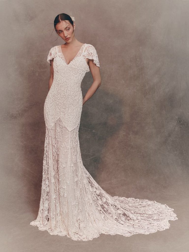 In questa foto, una modella indossa un abito da sposa Atelier Pronovias 2026 a semi sirena con ricami di perline e cristalli con manichette corte