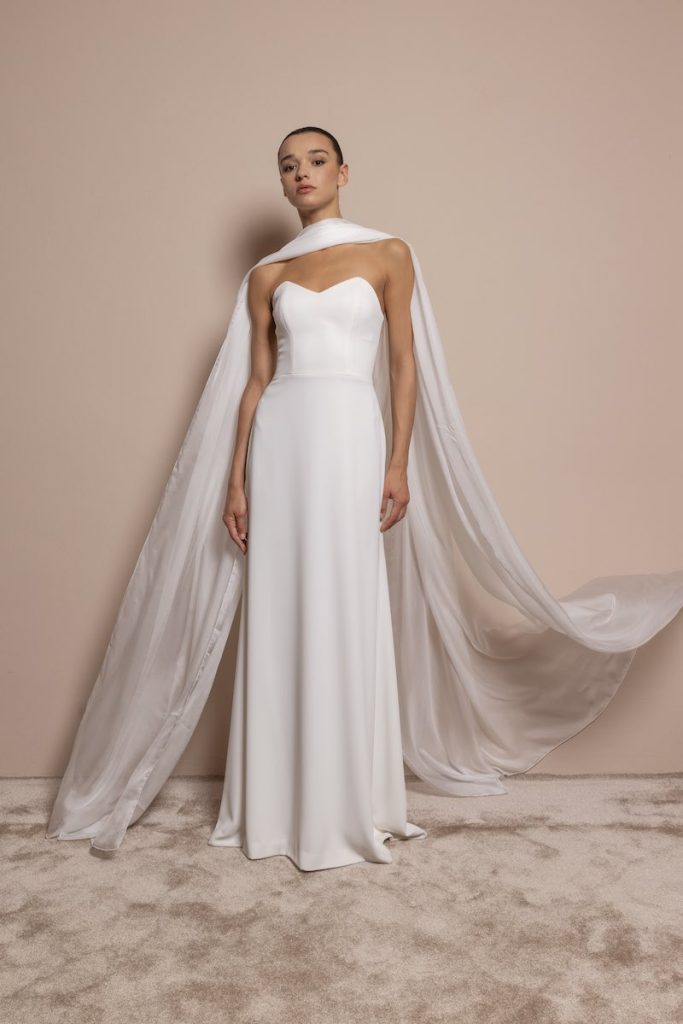 In questa foto, una modella posa indossando un abito da sposa di Daniela De Souza in cady di seta, modello scivolato, con scollo a cuore  abbinato ad una lunga in seta 