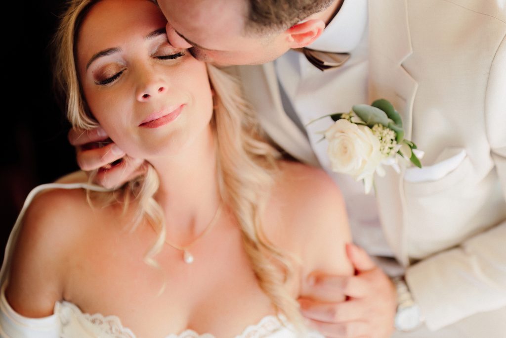 In questa foto, tratta dai matrimoni 2025 di Ilaria & Andrea, vediamo un primo piano intimo e dolcissimo degli sposi. Lo sposo bacia teneramente la fronte della sposa, che sorride con gli occhi chiusi, trasmettendo un senso di serenità e amore profondo. Il bouquet all’occhiello dello sposo e il trucco delicato della sposa completano un momento ricco di emozione.
