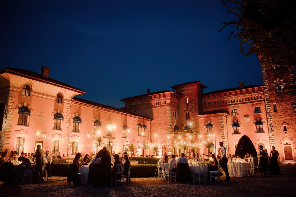 In questa foto notturna, gli invitati cenano all’aperto in una corte illuminata da luci calde e sospese, circondati da un’imponente architettura storica. L’atmosfera è elegante e festosa. La scena è parte del racconto visivo firmato matrimoni 2025 di Ilaria & Andrea.