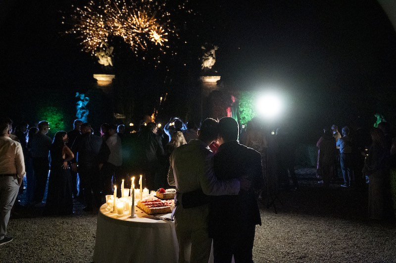 In questa foto, due sposi di spalle che guardano i fuochi d'artificio esplosi durante il taglio della torta nuziale