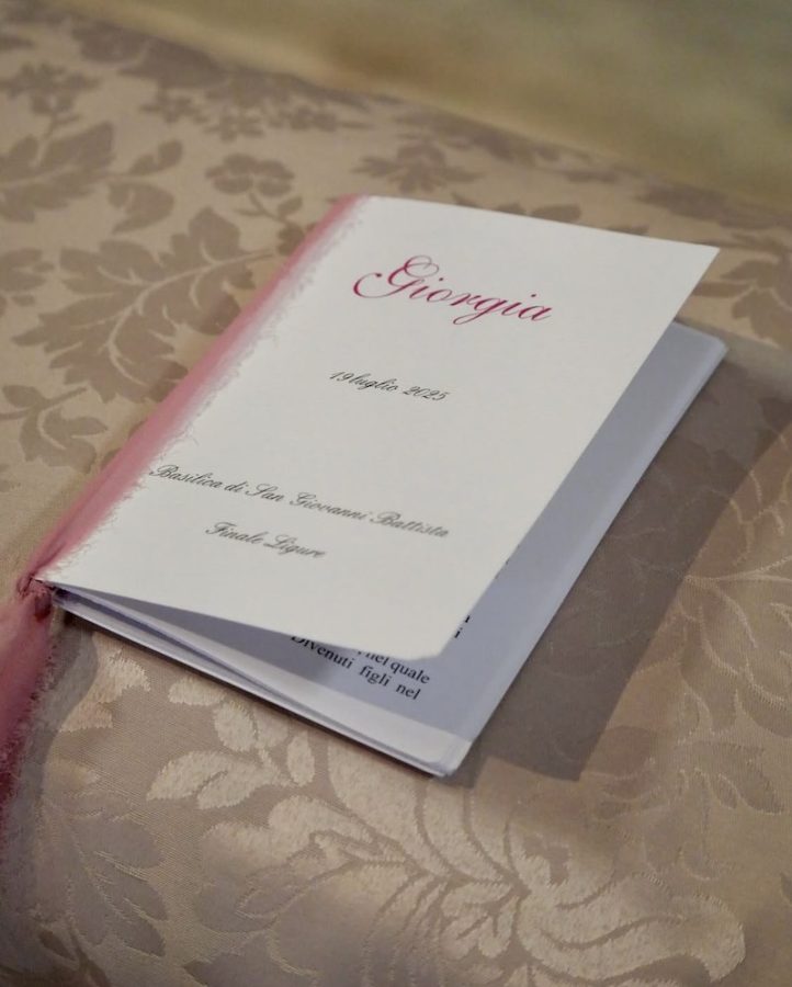 In questa foto, un libretto messa bianco con nastro di garza di colore rosa personalizzato con il nome della sposa