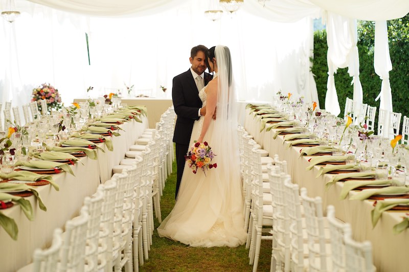 In questa foto due sposi tra due tavoli imperiali allestiti per un matrimonio a Palazzo Palitti nei toni del verde pistacchio