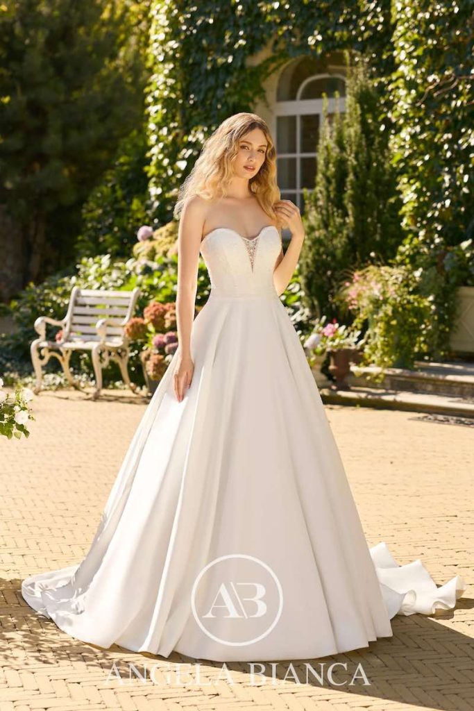 In questa foto, una modella posa indossando un abito da sposa Angela Bianca 2026 con silhouette ad Ad in mikado e scollo a cuore