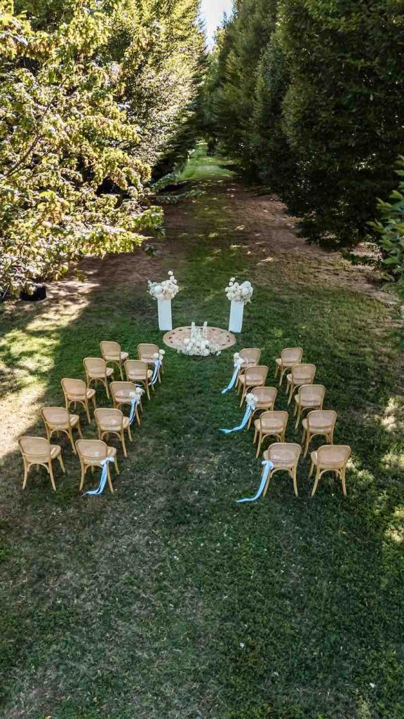 In questa foto, la vista dall'alto di un allestimento della cerimonia di nozze di uno Small Wedding a Villa Ormaneto realizzato con fiori di colore bianco e nastro di colore turchese e sedie in vimini da giardino