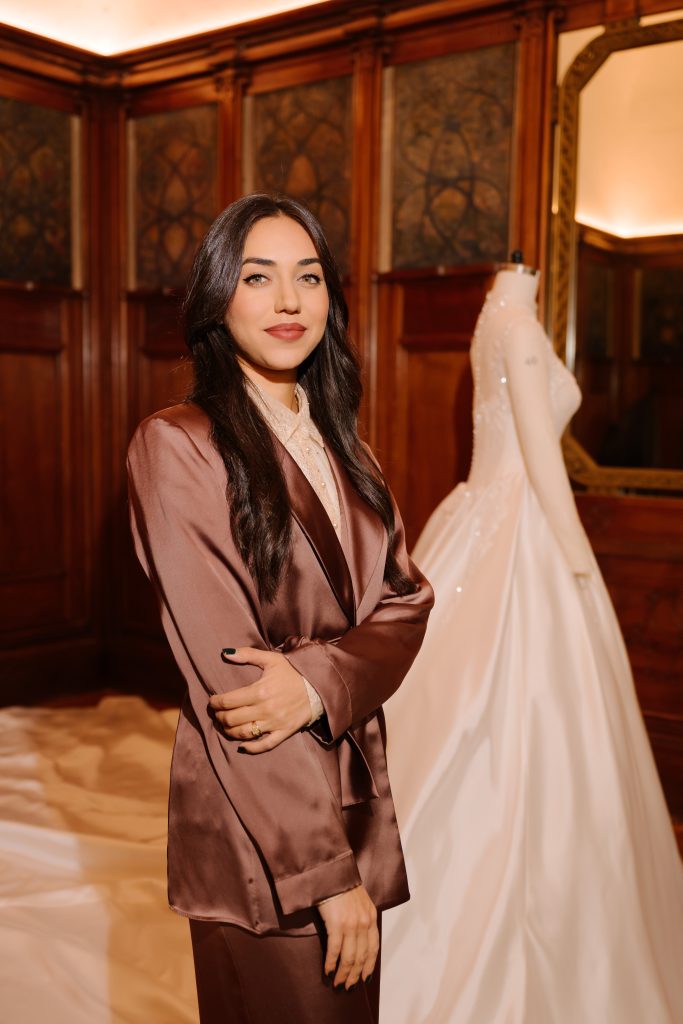 In questa foto si vede Silvia Falconi, Direttrice Creativa di Emé accanto ad uno degli abiti della collezione sposa 2026