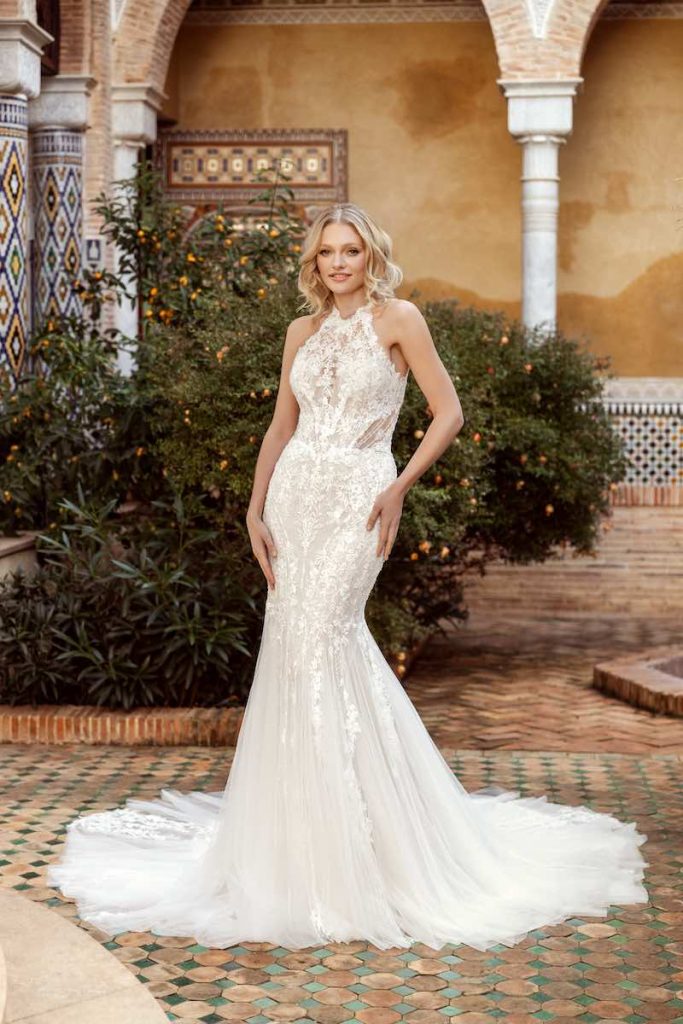 In questa foto, una modella posa indossando un abito da sposa Daniela Di Marino in pizzo, tulle e scollo all'americana
