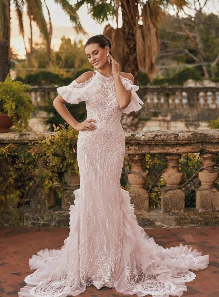 In questa foto, una modella posa indossando un abito da sposa a sirena con perline e paillettes di Monica Loretti